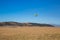 A rainbow colored hot air ballon floats above a valley and mountains.