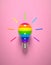 A rainbow-colored light bulb on a pink background.