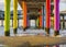 Rainbow colored stone poles under the pier of scheveningen beach the netherlands with sand and waves in the in the sea