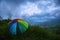 A rainbow colored umbrella enjoying dramatic monsoon landscape.