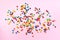 Rainbow colorful candies on pink background. Coated chocolate sweet pieces texture. Top view. Flat lay. Confetti for holidays,