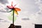 Rainbow coloured pinwheel held up against cloudy sky