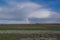 Rainbow with dark blue sky with clouds. grass and stones in foreground. People in the distance. The Netherlands: Waddensea. Unesco