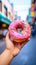 rainbow donut held in hand with street view, life style Authentic living