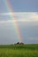 A rainbow extends skyward from a hill.