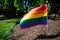 A Rainbow Flag in Black Mulch on a Suburban Front Lawn