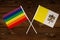 Rainbow flag LGBT and flag of Vatican on beautiful brown background with wooden texture. LGBT Pride Month. LGBTQ. LGBTQIA