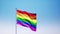 The rainbow flag, LGBT pride flag or gay pride flag waving at wind on clear blue sky