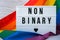 Rainbow flag with lightbox and text NON BINARY. Rainbow lgbtq flag made from silk material. Symbol of LGBTQ pride month
