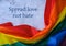 Rainbow flag with text SPREAD LOVE NOT HATE message. Rainbow lgbtq flag made from silk material. Symbol of LGBTQ pride