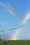 A rainbow formed by the mist from an agricultural sprinkler system.