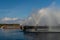 A rainbow forms in the jets of a fountain in a technical reservoir near a thermal power plant.  Industrial tourism