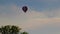 Rainbow hot air balloon ascends slowly slight left fades out and off