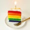 Rainbow  layered cake slice with candle
