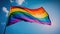 Rainbow LGBT flag waving in blue sky, generative AI