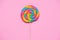 Rainbow lollipop swirl on wooden stick on pink