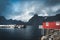 Rainbow ofer red houses rorbuer of Reine in Lofoten, Norway with red rorbu houses, clouds, rainy blue sky and sunny