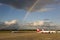 Rainbow over airplanes on airport Tegel, Berlin. Blue sky and dark rain clouds at same time.