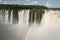 Rainbow over Devil`s throat cascade at Iguazu waterfalls, Argentina on a sunny day