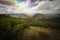 Rainbow over landscape and white clouds on blue sky