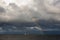 Rainbow over Sea, dark clouds and lighted container ship on Baltic Sea