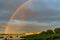 Rainbow over stony seacoast by sunset