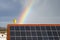 Rainbow over a tiled roof with solar panels. Satellite dish with a smile