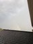 Rainbow peeking out of the clouds looking over a roof after a storm