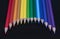 Rainbow pencil colors curve illusion on a black glass