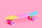 rainbow plastic Penny board skateboard isolated on pink background