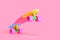 rainbow plastic Penny board skateboard isolated on pink background