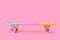 rainbow plastic Penny board skateboard isolated on pink background