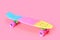 rainbow plastic Penny board skateboard isolated on pink background
