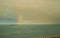 A rainbow after the rain and storms of the sea. Colorful types of clouds at sunrise, view of the sea horizon