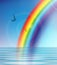 Rainbow road on blue sky above water birds flying