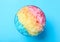 Rainbow shaving ice in glass dessert bowl on blue background, top view