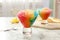Rainbow shaving ice in glass dessert bowls on marble table indoors, closeup