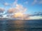 Rainbow shines through clouds over ocean off Kahala Beach