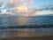 Rainbow shines through clouds over ocean off Kahala Beach with boat on the horizon