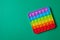 Rainbow silicone sensory antistress pop it toy on green background. Top view.