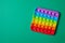 Rainbow silicone sensory antistress pop it toy on green background. Top view.