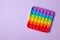 Rainbow silicone sensory antistress pop it toy on purple background. Top view.
