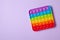 Rainbow silicone sensory antistress pop it toy on purple background. Top view.