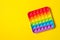 Rainbow silicone sensory antistress pop it toy on yellow background. Top view.