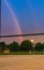 Rainbow in sky over evening baseball game, co-ed little league players second base and right field