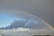 Rainbow in the sky after the rain. Blue sky. White clouds. The sky is visible through the storm clouds. High in the