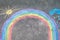 Rainbow sun and clouds with rain drops painted with colorful chalks on ground or asphalt in summer. Creative leisure for