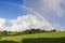 rainbow at sunrise over fields with blue sky