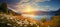 rainbow on sunset sky across a stunning vista landscape,mountains wildflowers sun flares