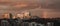 Rainbow at sunset on urban city with modern buildings and smoking chimney